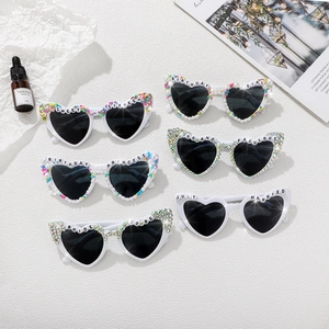 Flat lay of heart-shaped sunglasses with custom beads and birthday phrases on white background