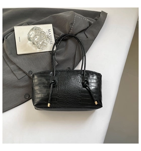 Détail d'un cabas noir à motif crocodile avec décoration de poignée à nœuds