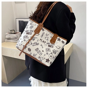 Detail of white tote bag with street style graffiti print and brown leather handles