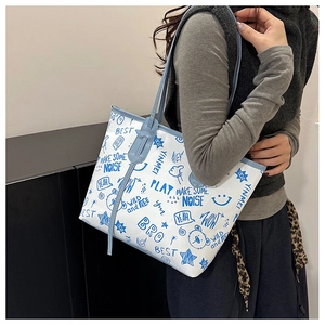 Close-up of white tote bag with blue graffiti prints and leather shoulder straps