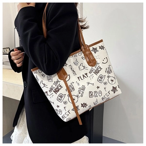Detail of graffiti print tote bag with brown leather handles shown in a lifestyle setting