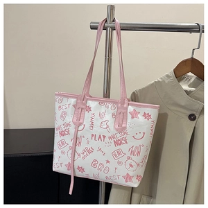 Close-up of a white leather tote bag featuring pink graffiti prints and cartoon patterns
