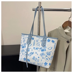 Detail of white tote bag with blue graffiti prints and slender handles on a hanger