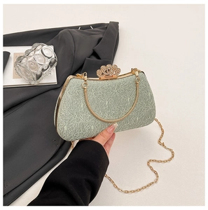 Detail of light green lace evening bag featuring golden metal frame and crown rhinestone clasp