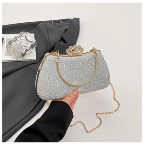 Detail of silver evening clutch featuring a gold metal frame and a diamond crown clasp