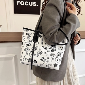 Off-white tote bag with graffiti prints and slim black shoulder straps on a model