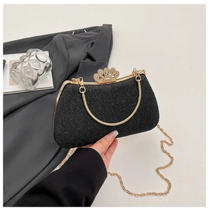 Detailed macro view of black sequin evening bag with gold crown rhinestone clasp and chains
