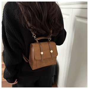 Detailed view of a vintage brown PU leather backpack on a black knit sweater