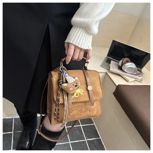 Detailed shot of brown frosted texture bag with cute bear pendant and metal handle