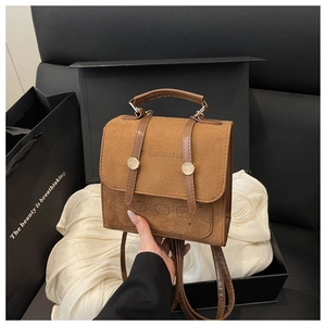 Detailed close-up of brown suede mini backpack with bear embossing in a gift box setup