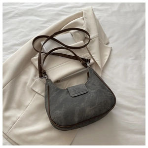 Detail view of grey crescent shoulder bag with brown leather trim and matte suede texture