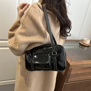 Chic black glossy shoulder bag with white contrast stitching on beige wool coat