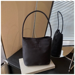 Detalle de bolso de hombro en nylon negro con bordado Hope and Future bajo luz natural