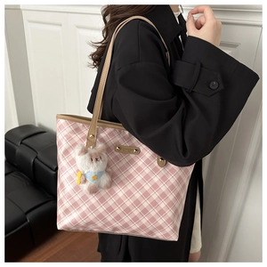 Detail of pink plaid canvas tote bag with brown handles and a white plush bear charm