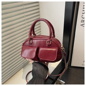 Gros plan du sac fourre-tout rouge foncé avec poches avant et accessoires dorés