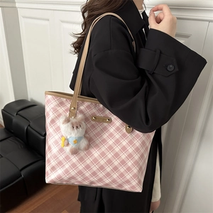 Pink plaid tote bag with large capacity and bear charm, styled on a black trench coat