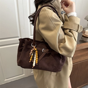 Brown suede tote bag with decorative bead tassel charm shown from a 45-degree angle