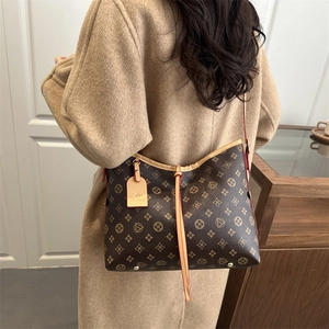 Classic dark brown monogram hobo bag with leather straps on model wearing a beige coat
