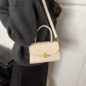 Sac bandoulière crème minimaliste avec fermoir doré et poignée sur un mannequin