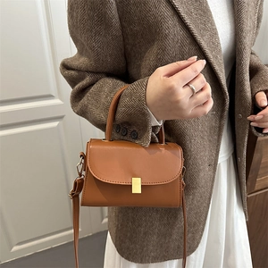 Petit sac bandoulière marron chic avec boucle dorée sur un mannequin en blazer élégant