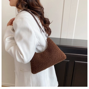 Brown teddy fleece tote bag worn on shoulder with leather strap and white blazer jacket