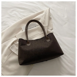 Detail of large brown tote bag with subtle leopard pattern on stylish beige blazer