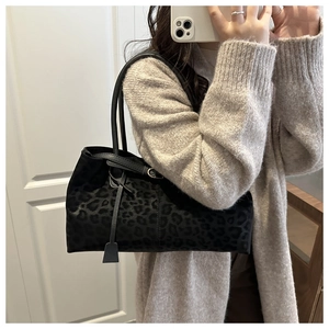 Close-up of black leopard print tote bag with soft suede texture and leather handle