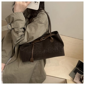 Detail of leopard print tote bag with brown leather straps and metallic buckle detail