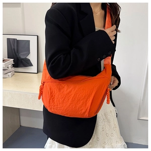 Detail of bright orange nylon crescent crossbody bag with minimalist shoulder strap style