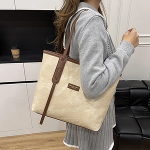 Minimalist beige canvas tote bag with brown leather straps shown on a female model