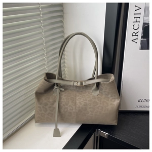 Detail of taupe leopard print tote bag with decorative metal buckle and tag pendant