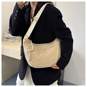 Detail of beige nylon dumpling bag with woven zipper pull and adjustable strap