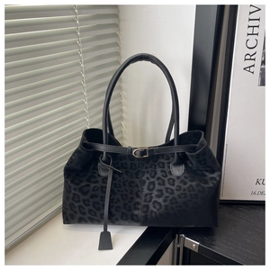 Close-up of black leopard print tote bag with subtle matte texture and handle detail