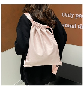 Detailed back view of a minimalist pink drawstring bucket bag worn by a model