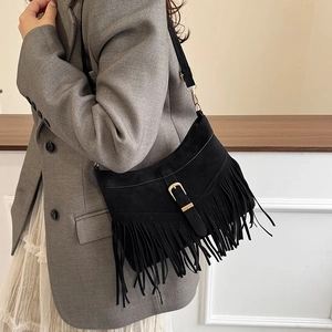 Retro black suede tassel shoulder bag with gold buckle on a model in a gray blazer