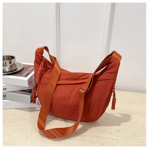 Dettaglio della borsa in nylon rosso mattone con tiretto intrecciato e tracolla regolabile