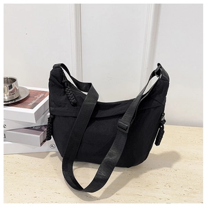 Dettaglio borsa a mezzaluna in nylon nero con tirante in tessuto su base in pietra