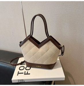Detail of quilted beige fabric tote bag with brown leather trim and golden JBH branding