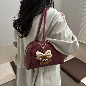 Quilted burgundy boston bag with cute plush pendant styled with a beige trench coat