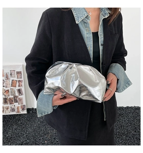 Silver metallic PU leather cloud clutch bag with pleated texture held by a model