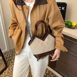 Quilted beige canvas and brown leather tote bag worn with a casual khaki outfit