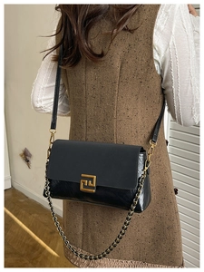 Detail of black shoulder bag with matte leather and glossy pleated texture on model