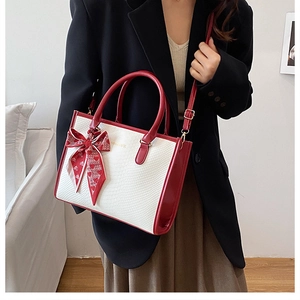 Detail view of red and white color-block tote bag with snake skin texture and bow