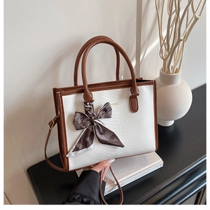Detail of white snakeskin texture handbag with brown leather trim and heart print scarf