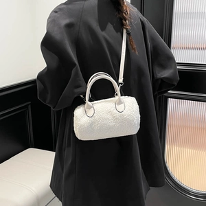 White lamb-fleece cylinder bag with leather straps on model wearing a black coat