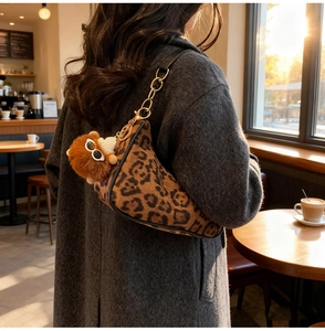 Detail of leopard print crescent bag with golden chain and plush monkey charm on shoulder