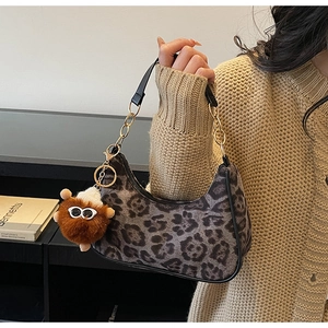 Detail of leopard print shoulder bag with gold chain strap and brown plush monster charm