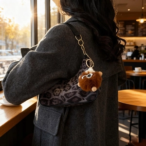 Stylish leopard print saddle bag with chain strap and teddy bear charm on model