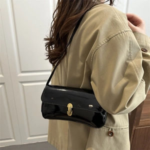 French vintage black patent leather shoulder bag with gold clasp shown on a trench coat