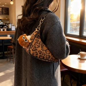 Retro leopard print crescent shoulder bag with plush charm and chain strap in cafe setting